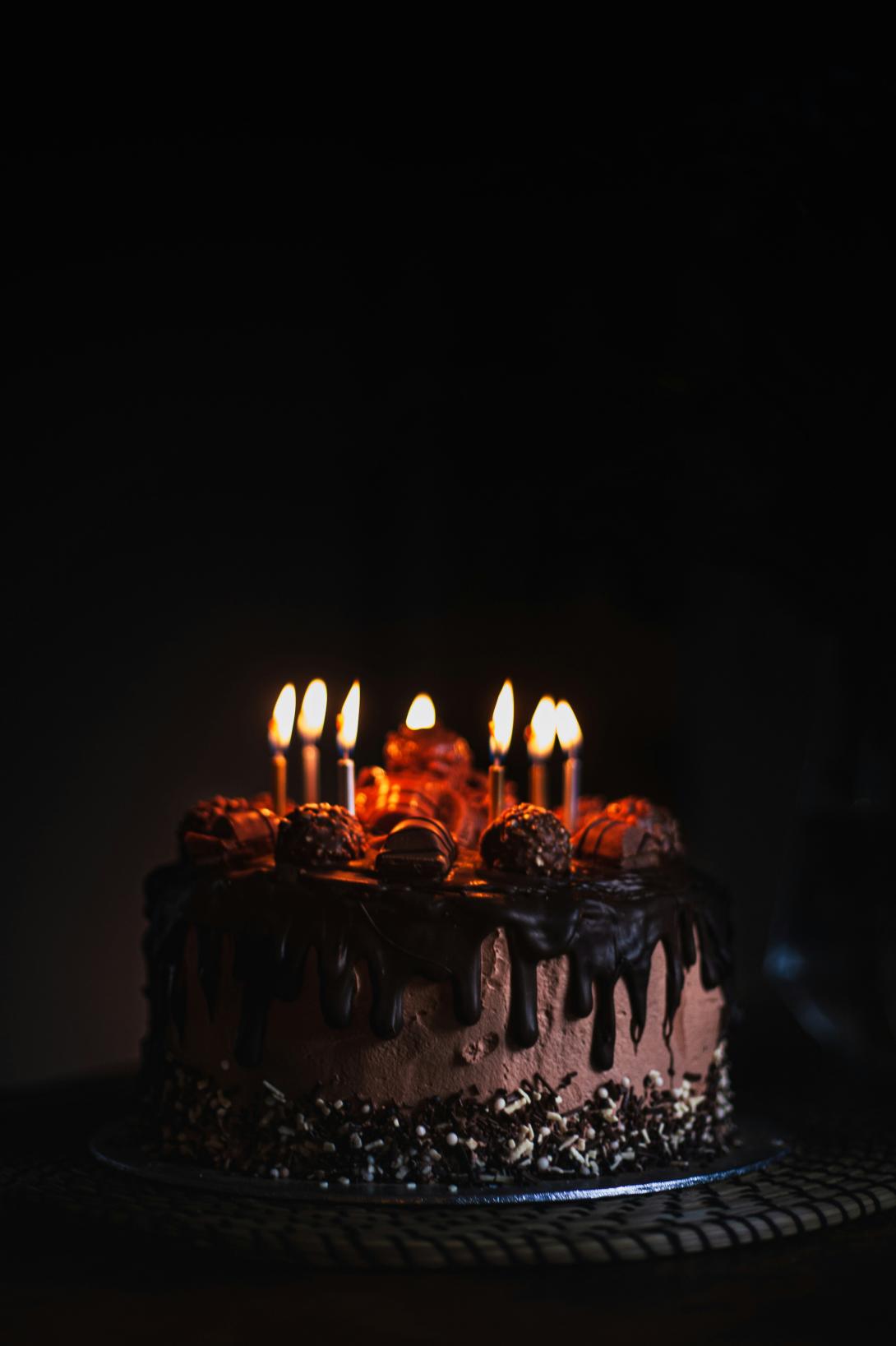 Birthday cake with lit candles in the dark