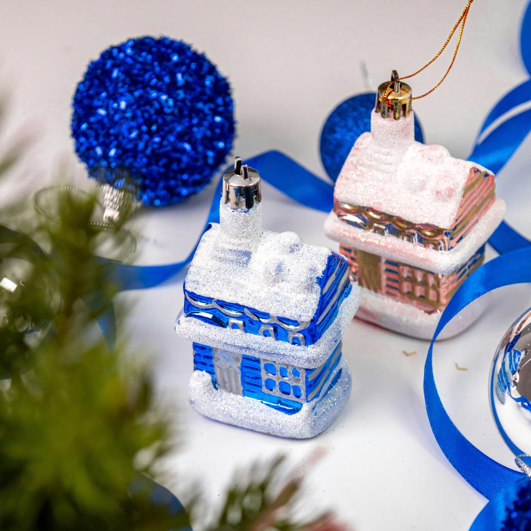 Picture of a blue glass sphere ornament and two miniature house shaped ornaments (one blue with a snow covered roof and one brown with a snow covered roof)